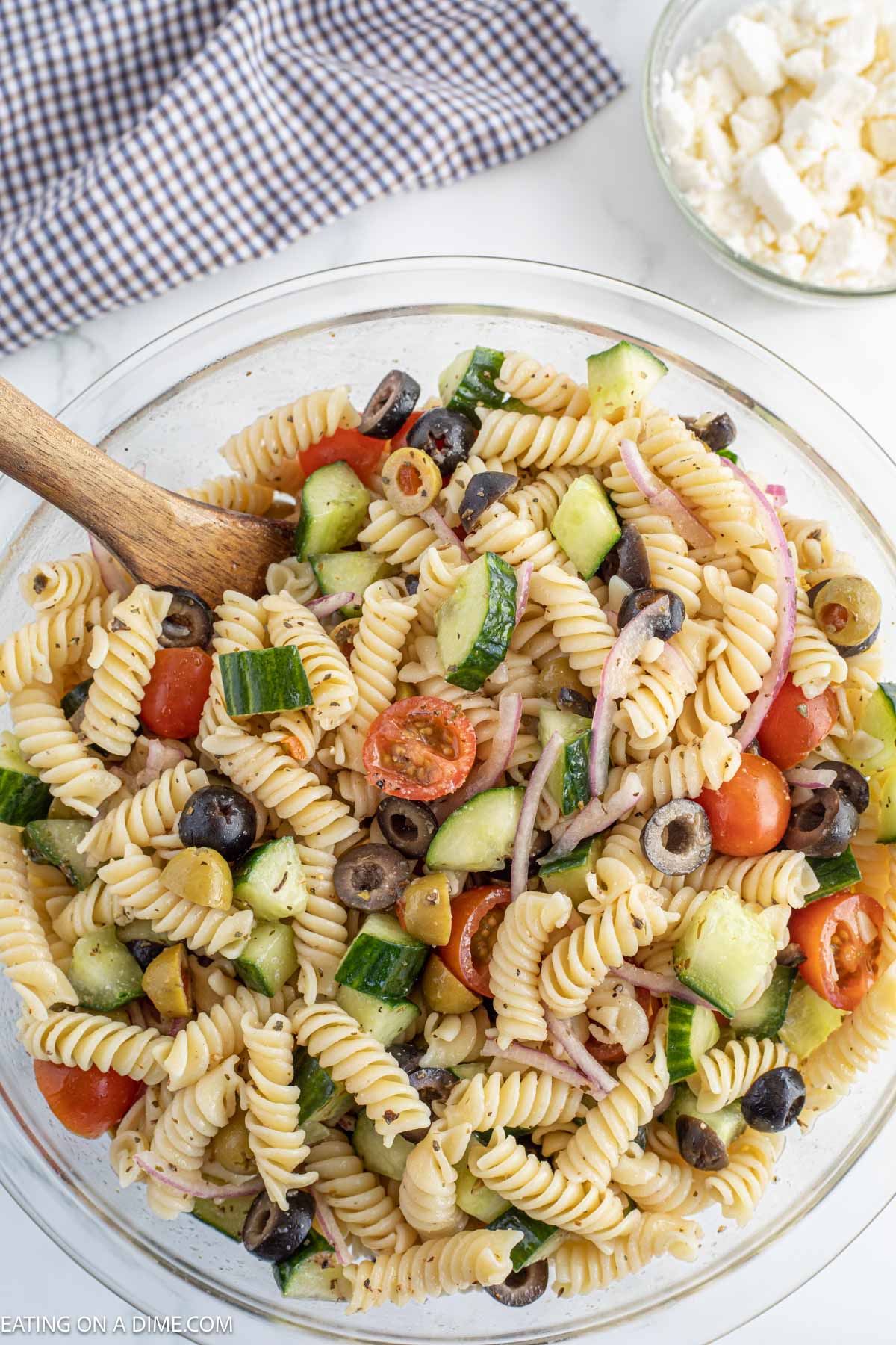 Mediterranean Pasta Salad in a bowl with a wooden spoon