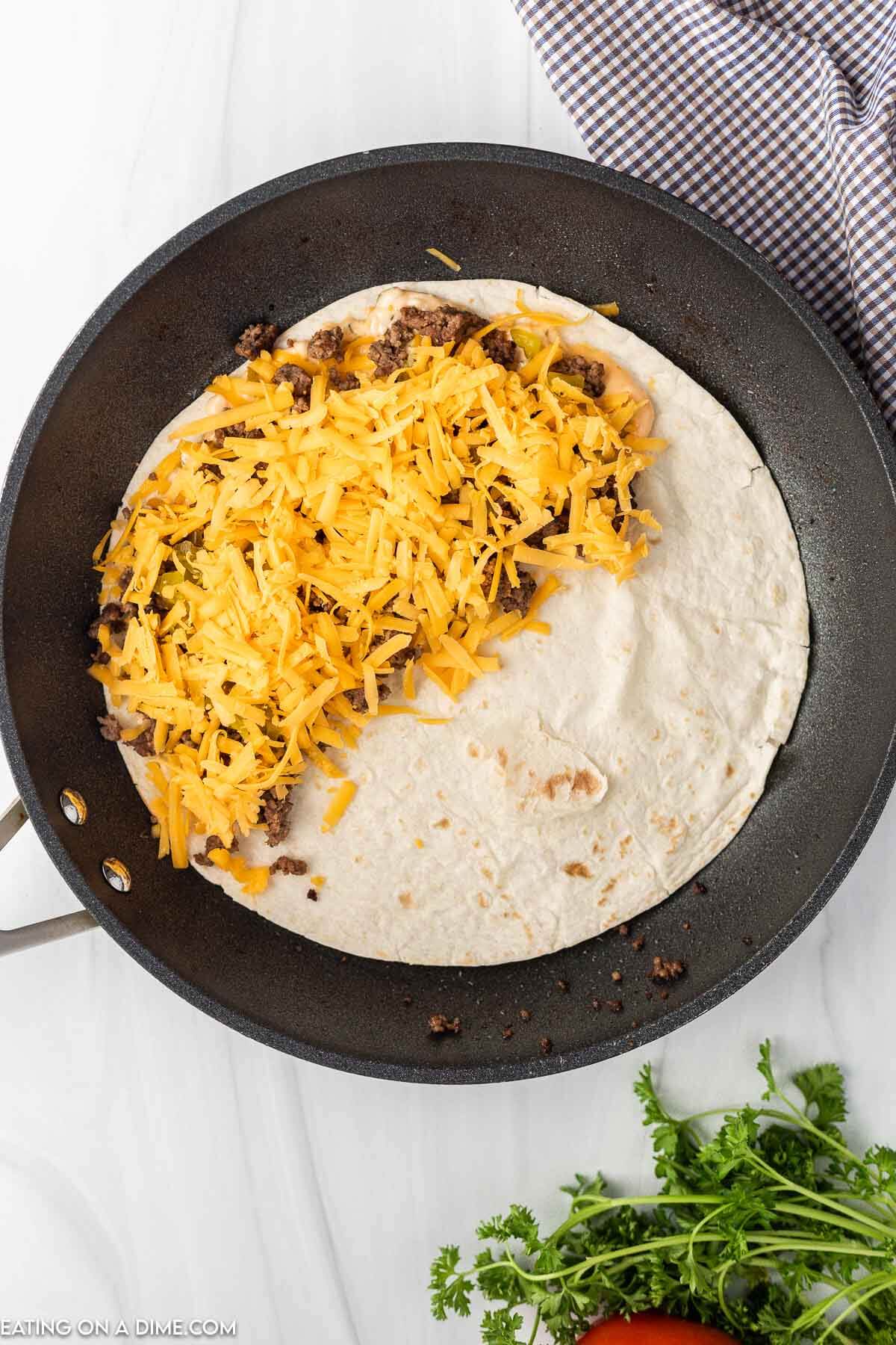 Topping the tortilla with beef, cheese and sauce