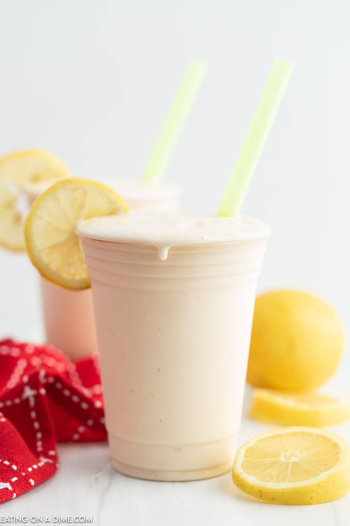 Frosted Lemonade in a cup with slice lemons and a straw