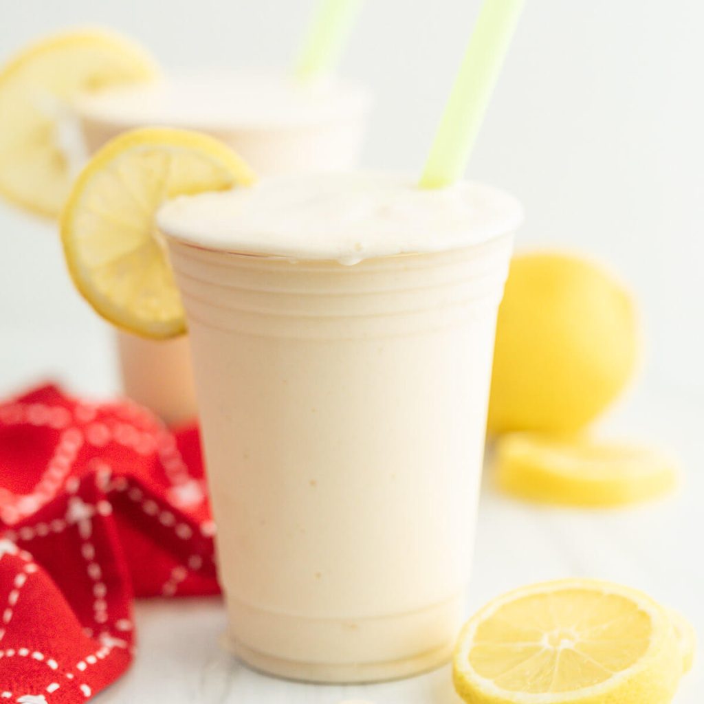 Frosted Lemonade in a cup with slice lemons and a straw