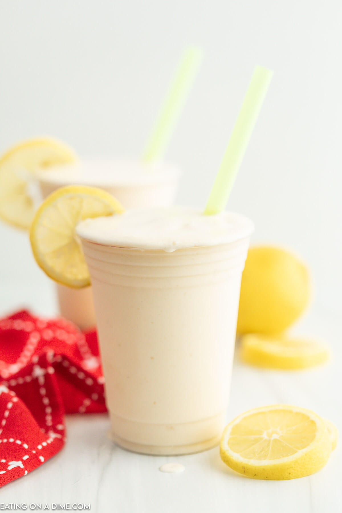 Frosted Lemonade in a cup with slice lemons and a straw