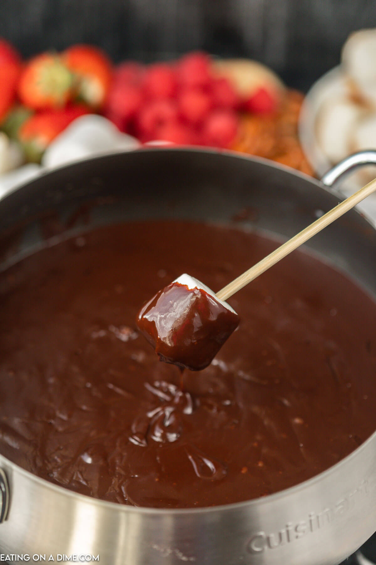 Chocolate Fondue in a sauce pan and dipping a marshmallow in it