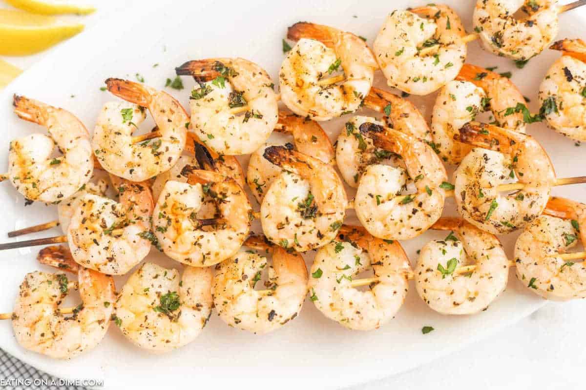 Grilled Shrimp Skewers stacked on a white platter.