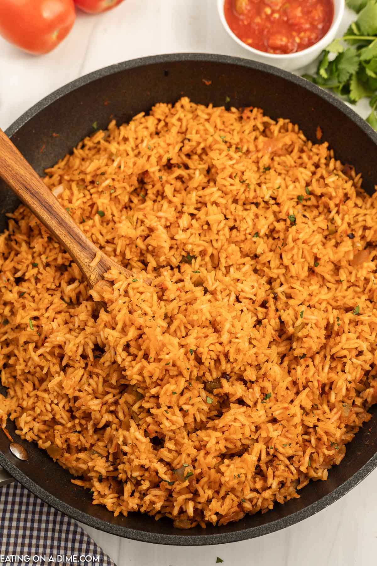 Close up image of Spanish Rice in a skillet with a wooden spoon
