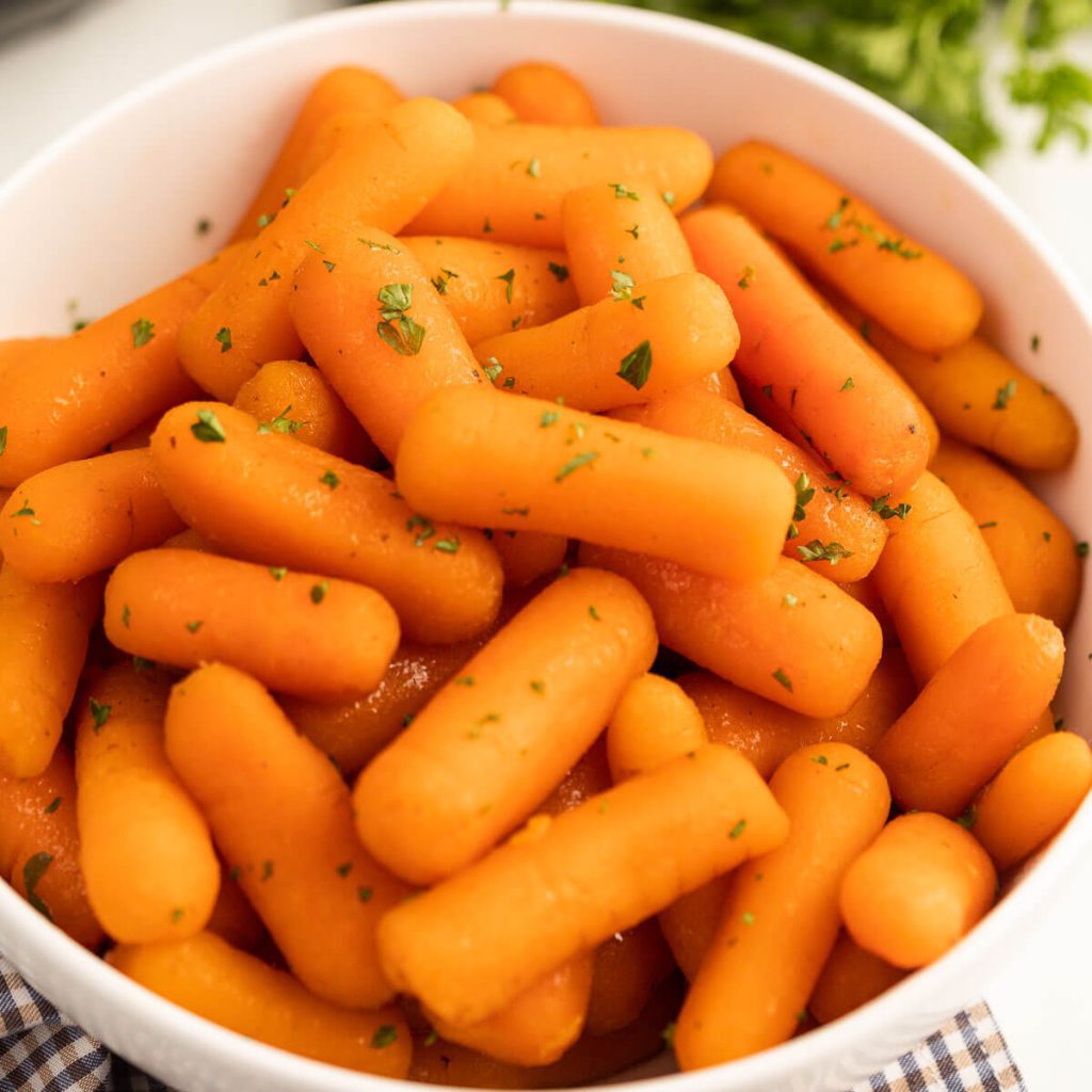 Cooked Baby Carrots in a white bowl