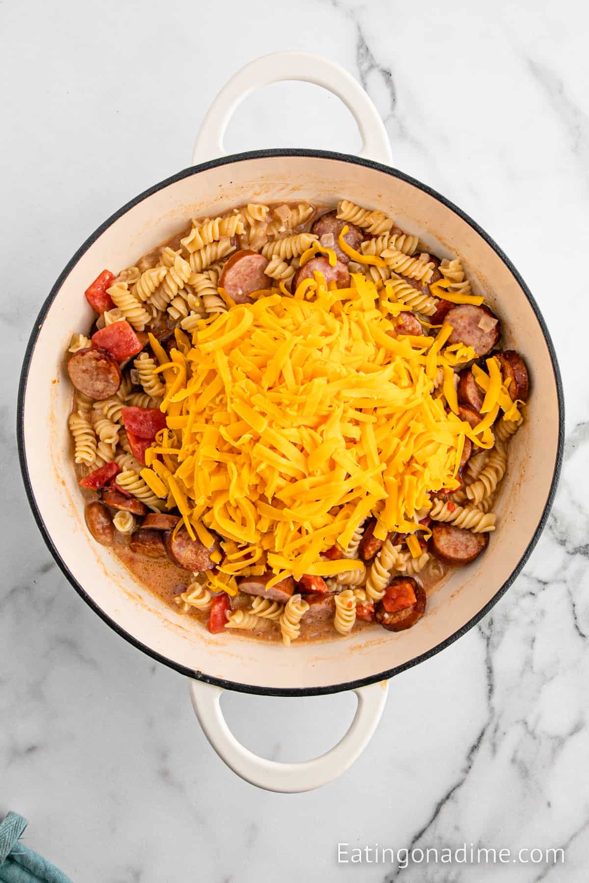 Topping the pasta mixture with shredded cheese