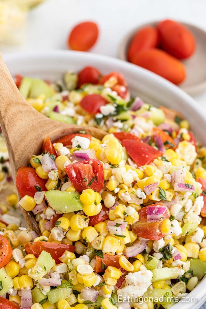 Corn Salad in a bowl with a wooden spoon