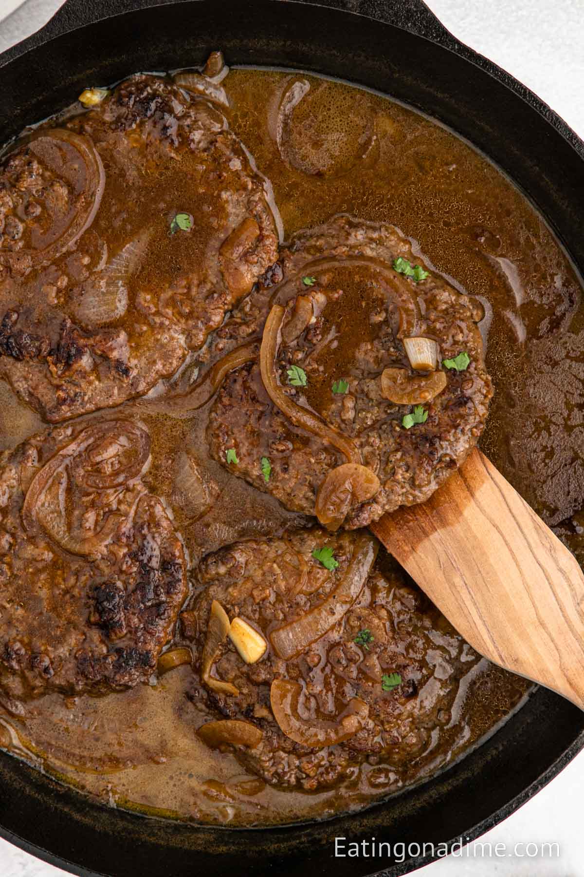 Cube Steak and gravy in a skillet with a wooden spoon