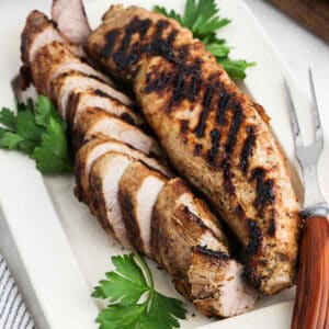 Grilled Pork Tenderloin sliced on a white platter.
