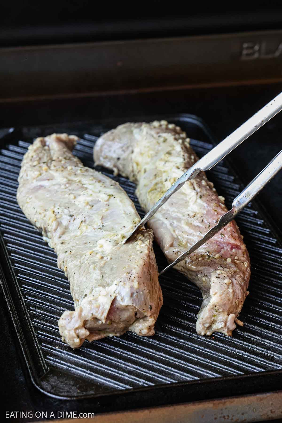 Marinated pork tenderloin placed on the grill.