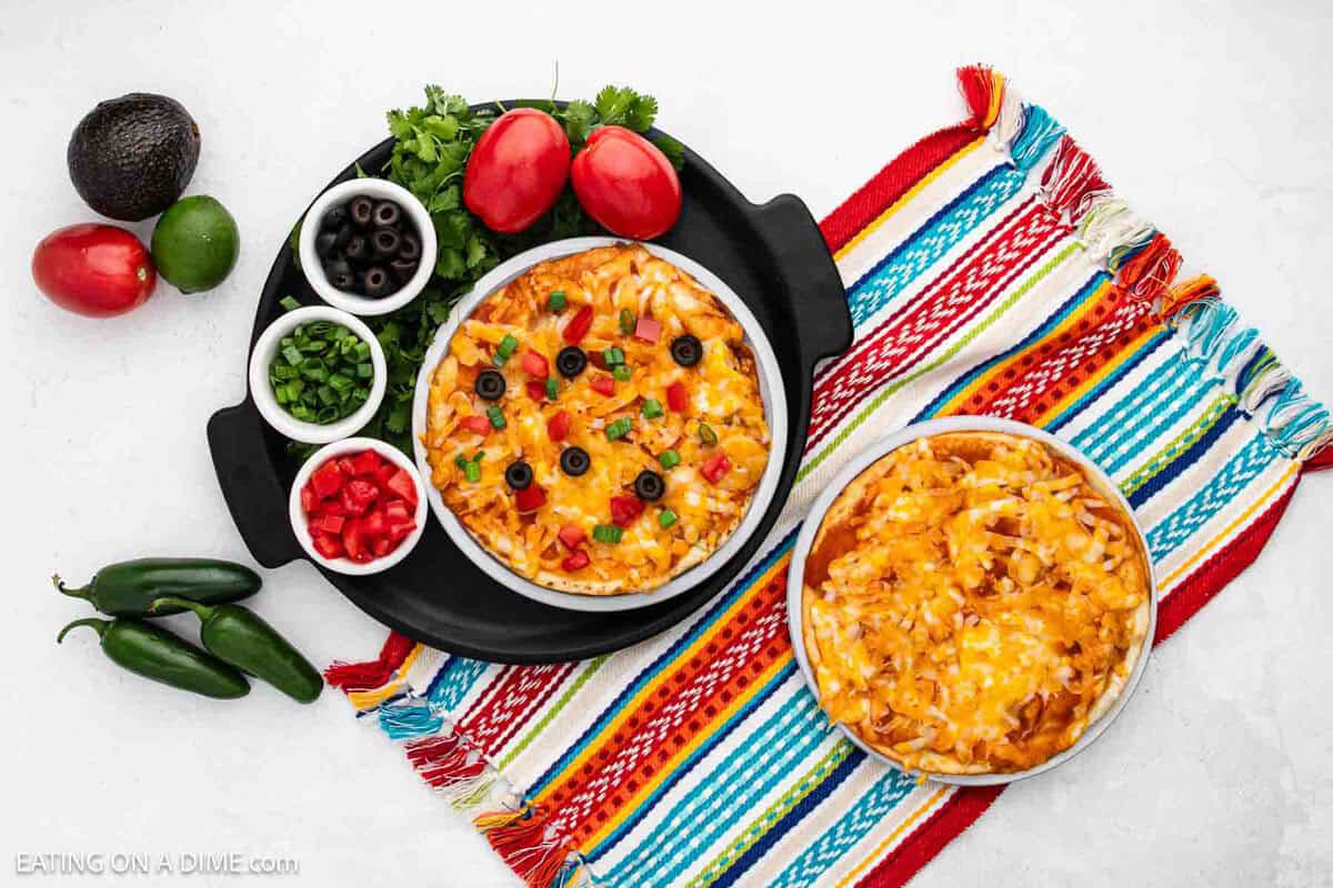2 Taco Bell Mexican Pizzas one topped with black olives, greens onions and tomatoes and the other just has melted cheese.