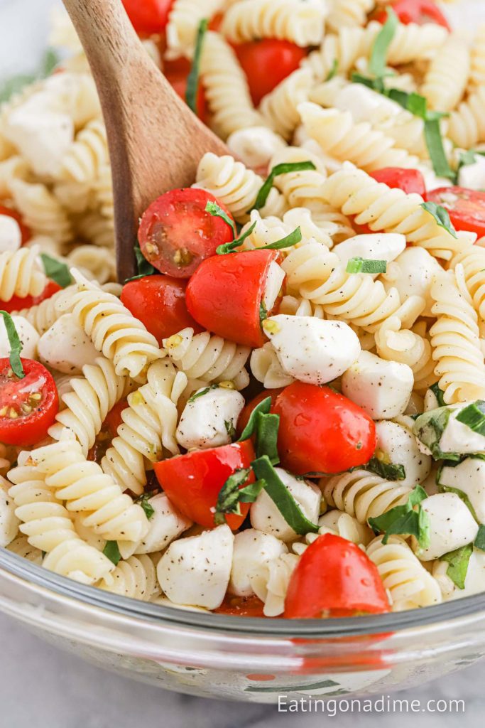 Caprese Pasta Salad in a bowl with a wooden spoon