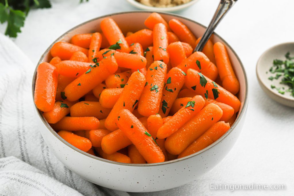 Baby Carrots in a bowl with a serving on a spoon