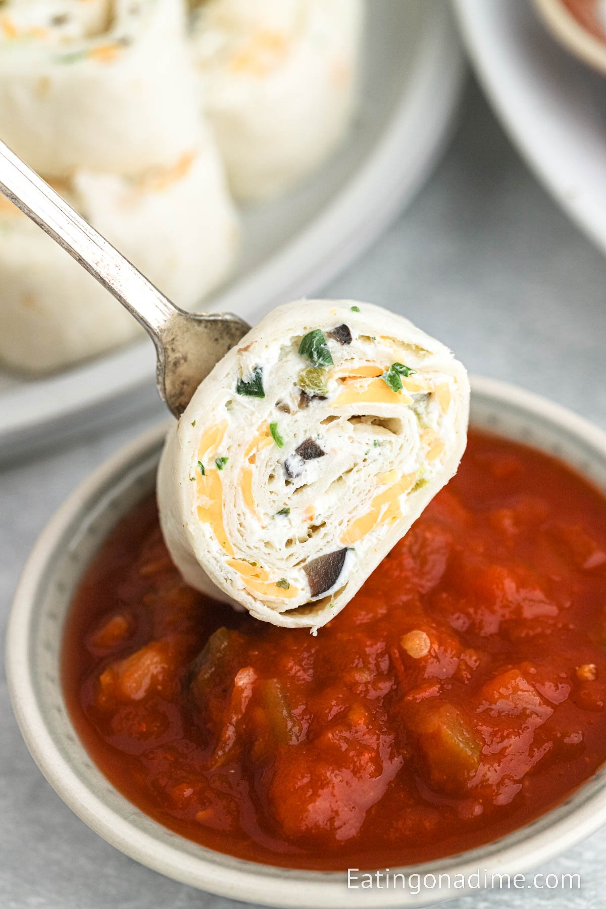 Cream Cheese Tortilla Rolls up dipping into salsa