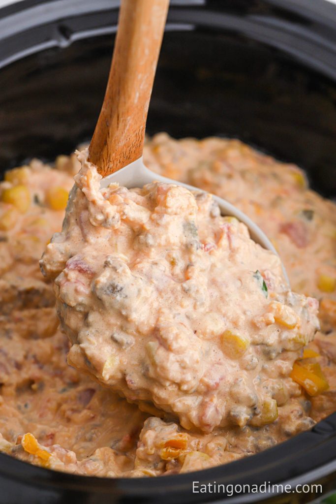 Cowboy Crack Dip in the slow cooker with a serving on a ladle