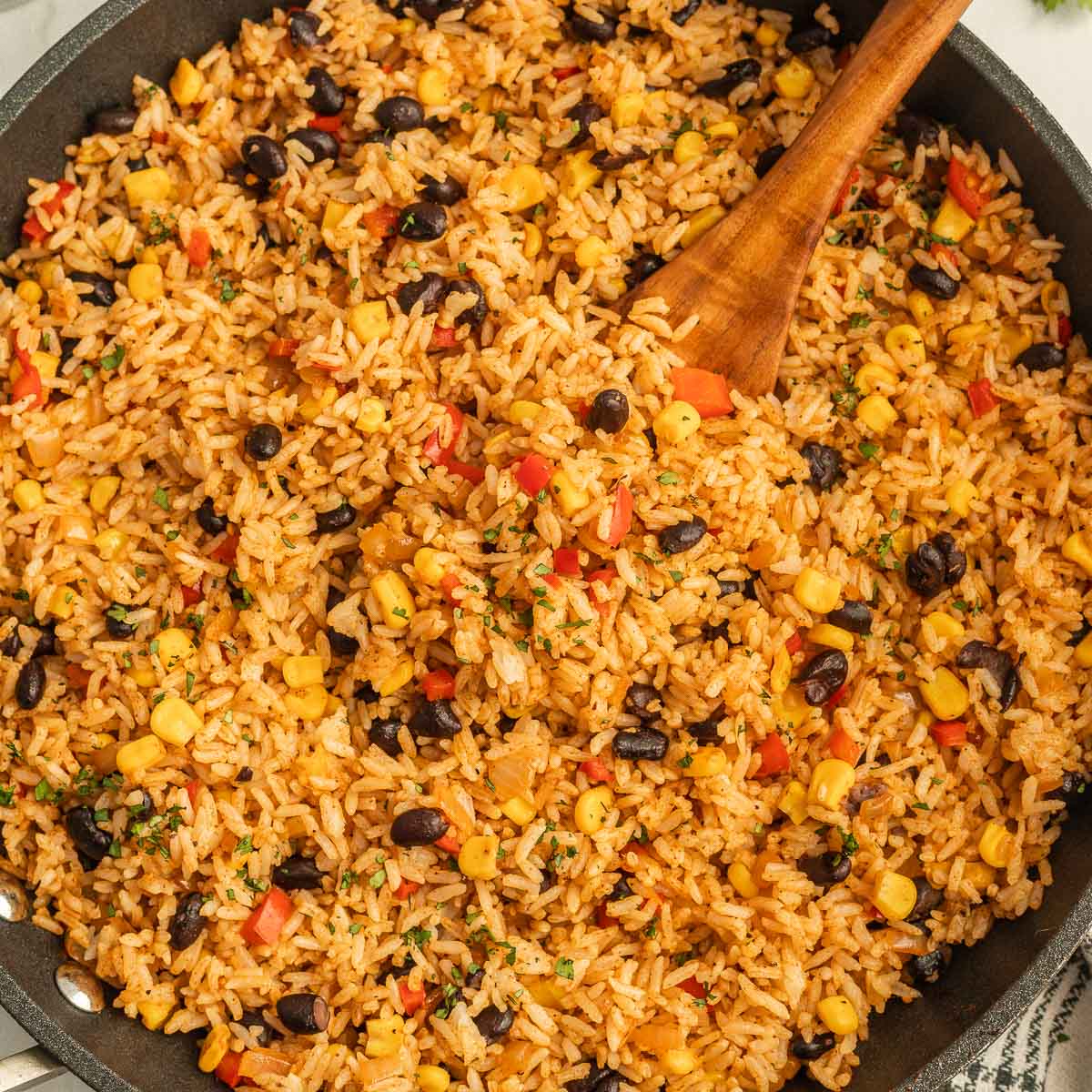 Mexican Fried Rice in a skillet with a wooden spoon