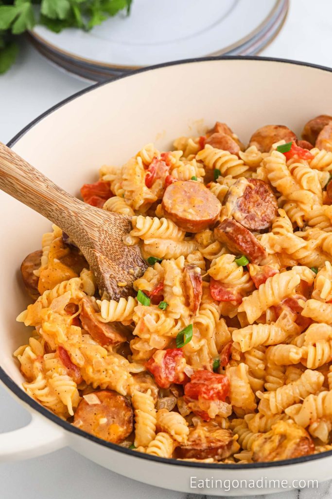 Kielbasa and Pasta in a dish with a serving on a wooden spoon
