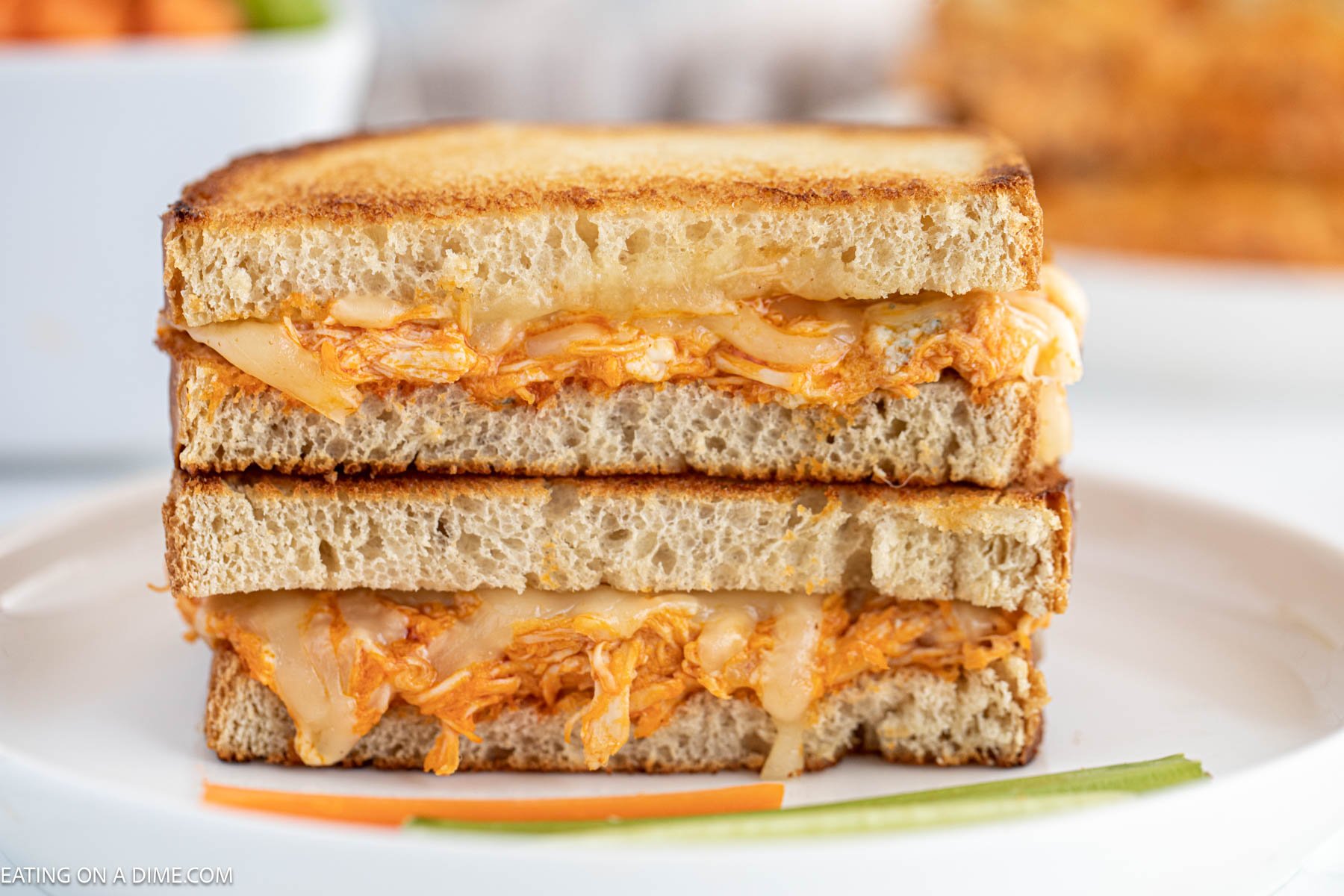 Buffalo Grilled Cheese Sandwich stacked on a plate with celery and carrots