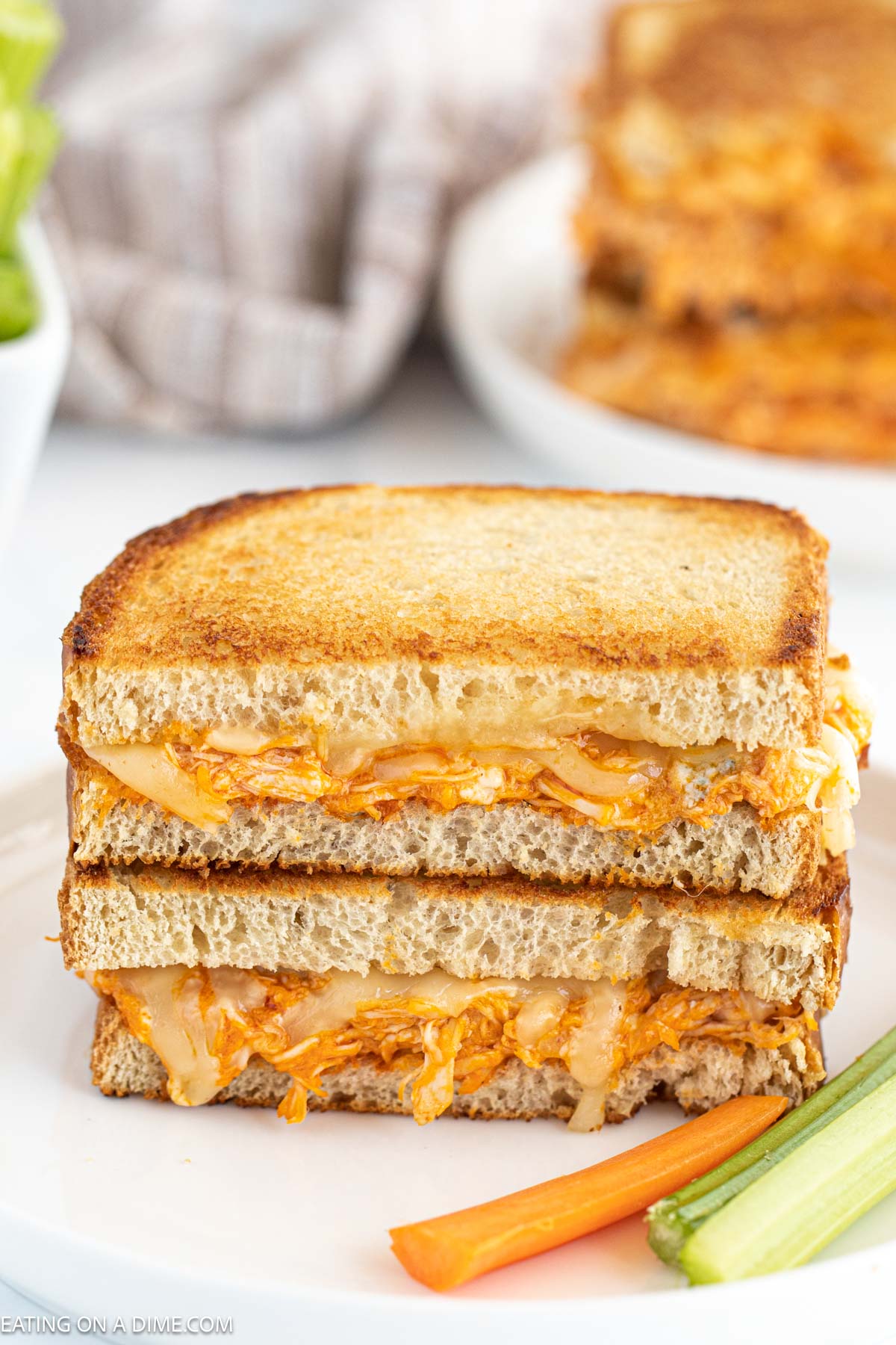 Buffalo Grilled Cheese Sandwich stacked on a plate with celery and carrots