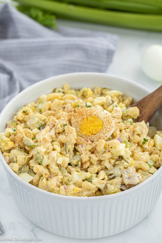 Deviled egg pasta salad in a bowl with a wooden spoon