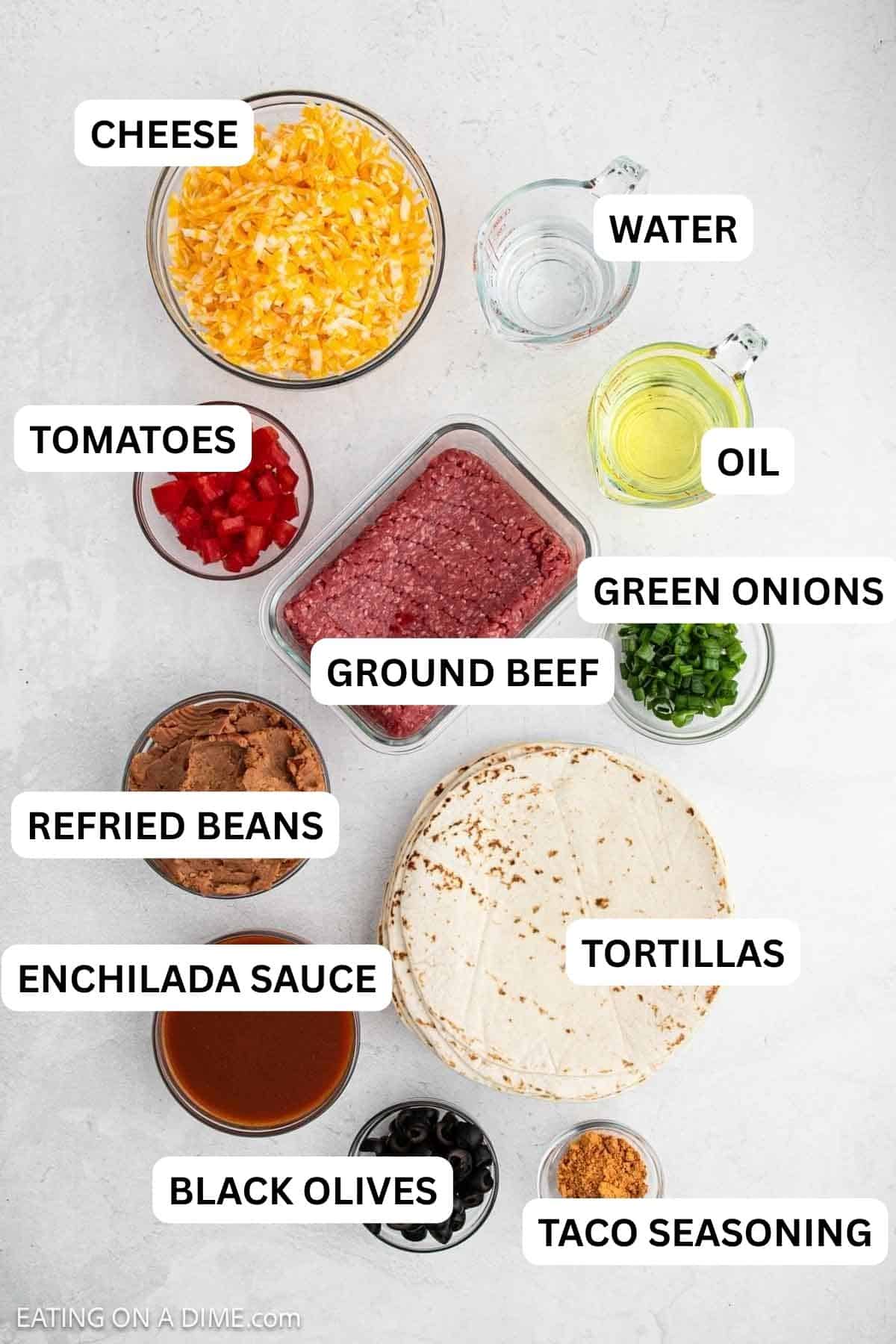 Ingredients needed for this recipe which includes tortillas, ground beef, taco seasoning, refried beans, red enchilada sauce, cheese, and oil.