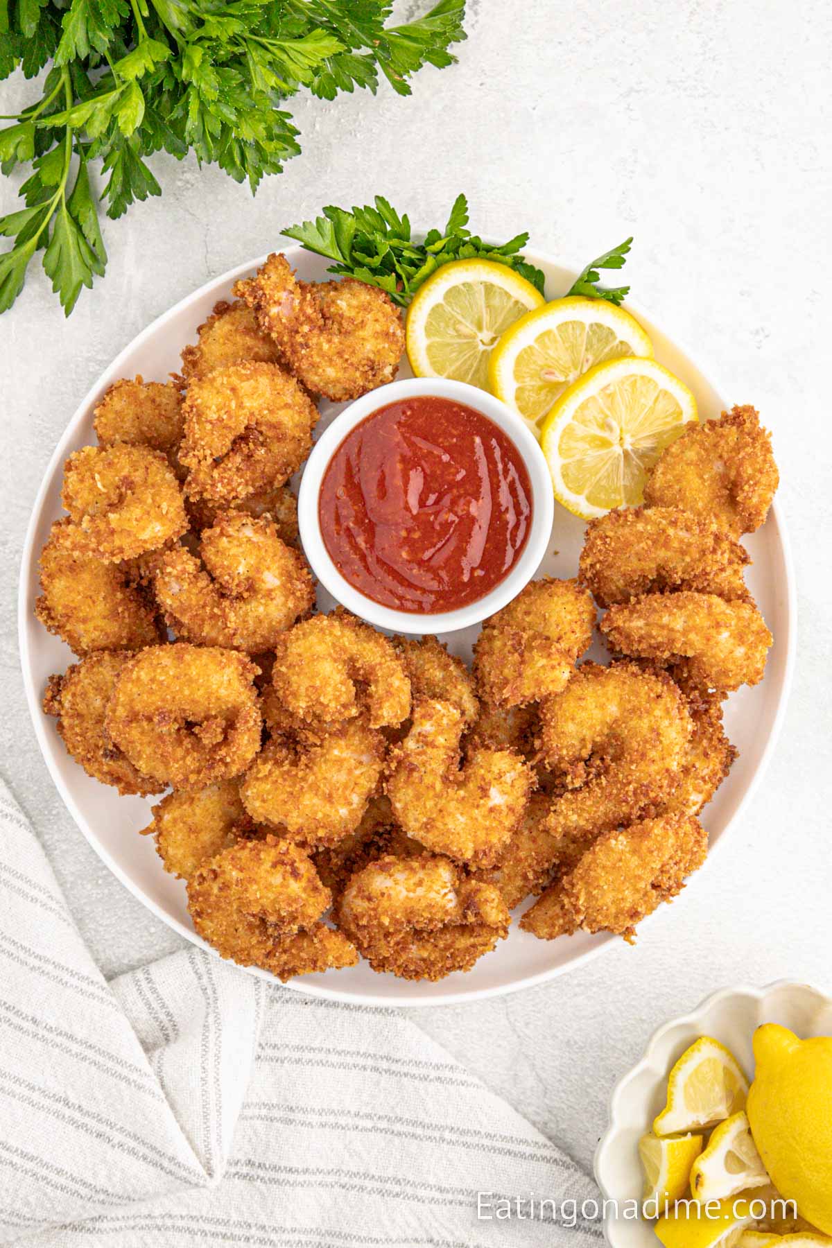 Panko Shrimp stacked on a white plate with a side of dipping sauce