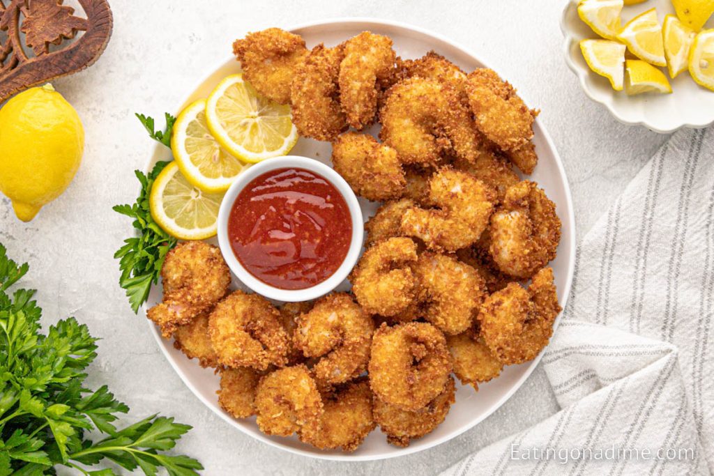 Panko Shrimp stacked on a white plate with a side of dipping sauce