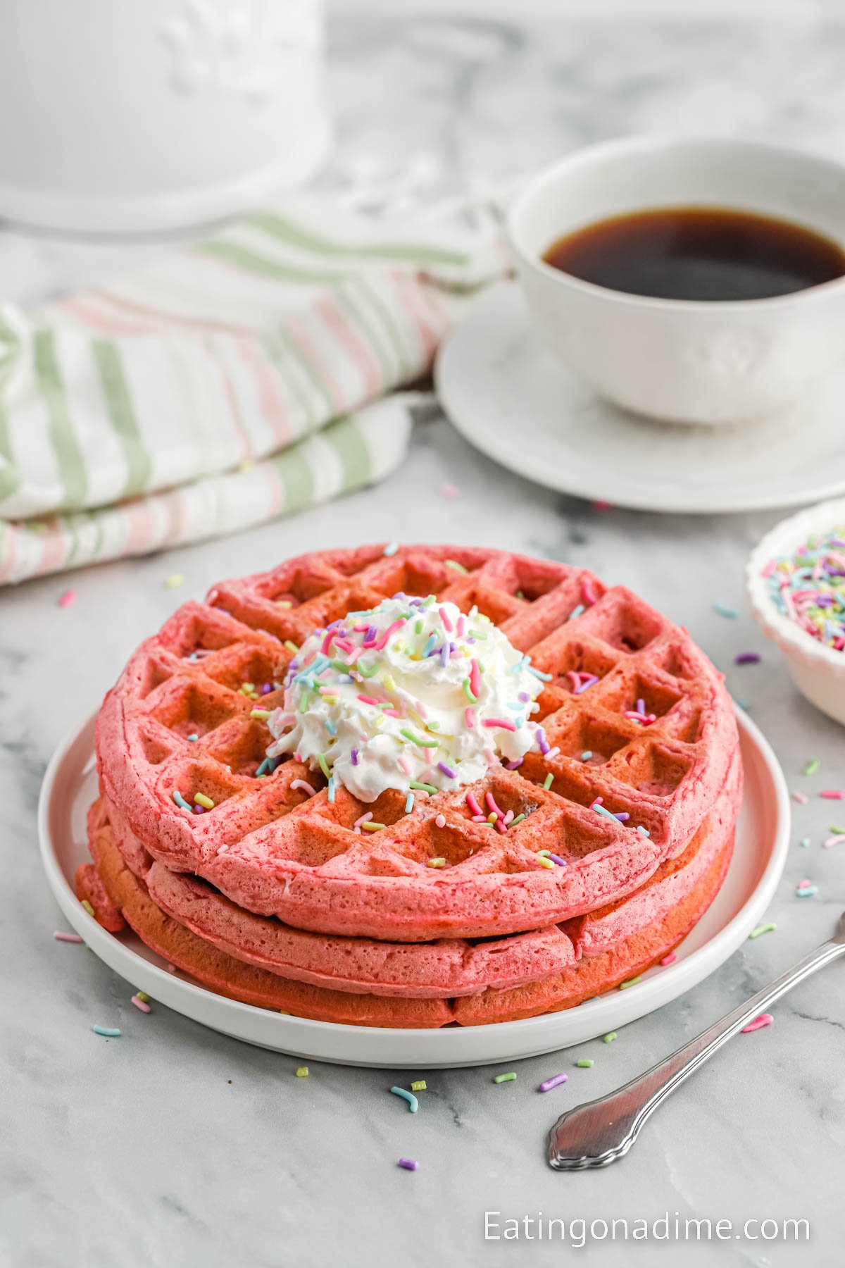 Pink Waffles Stacked on a white plate and topped with glaze and sprinkles