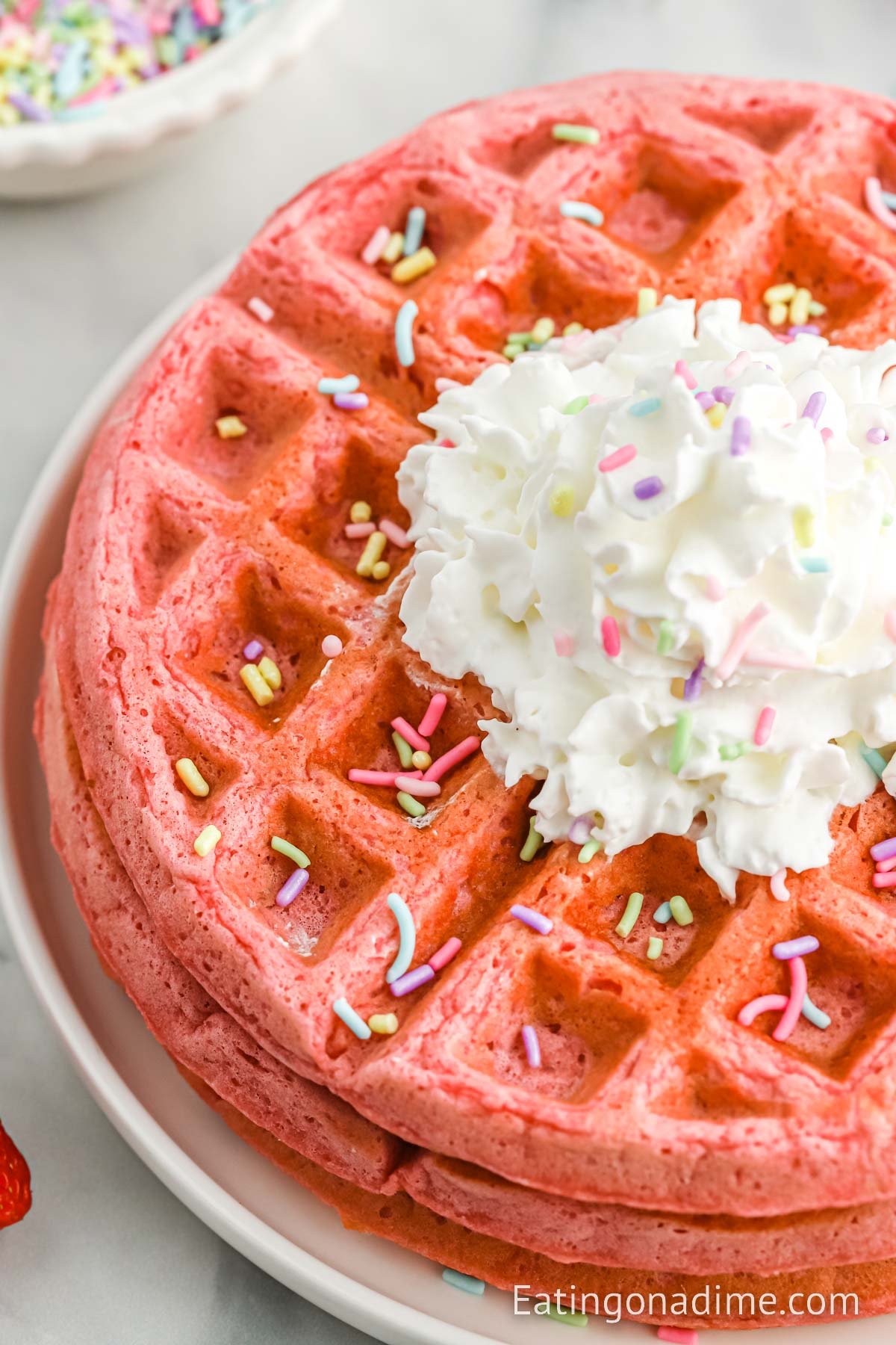 Pink Waffles Stacked on a white plate and topped with glaze and sprinkles