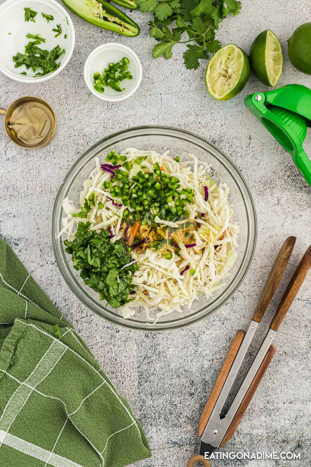Shredded coleslaw in a bowl topped with cilantro and chopped jalapenos