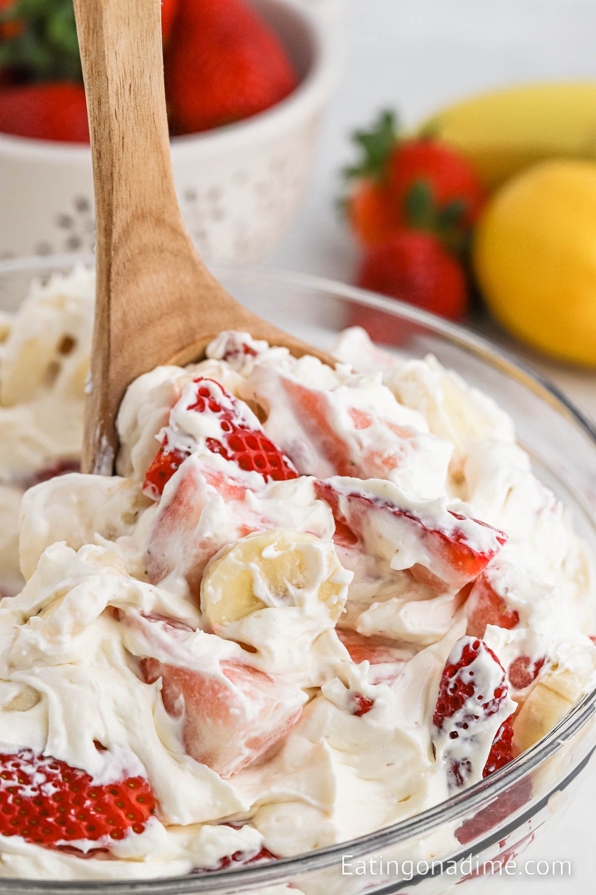 Fruit salad in a bowl with a serving on a wooden spoon