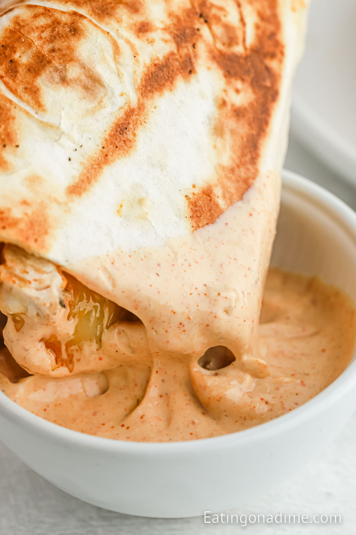 Dipping chicken quesadillas in a bowl of sauce