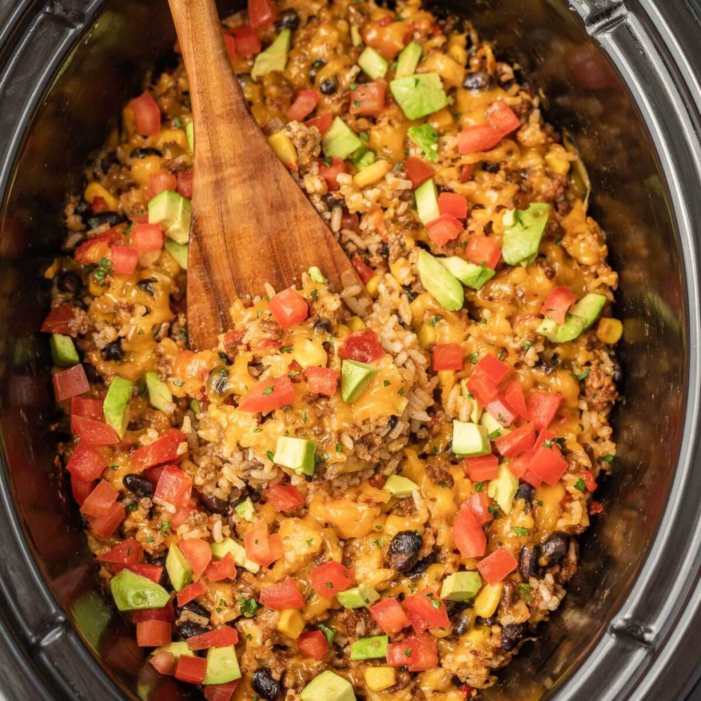 Taco Casserole in a slow cooker with a wooden spoon