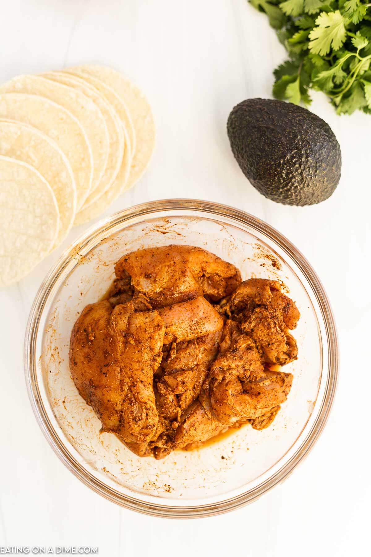 Chicken in a bowl with seasoning. 