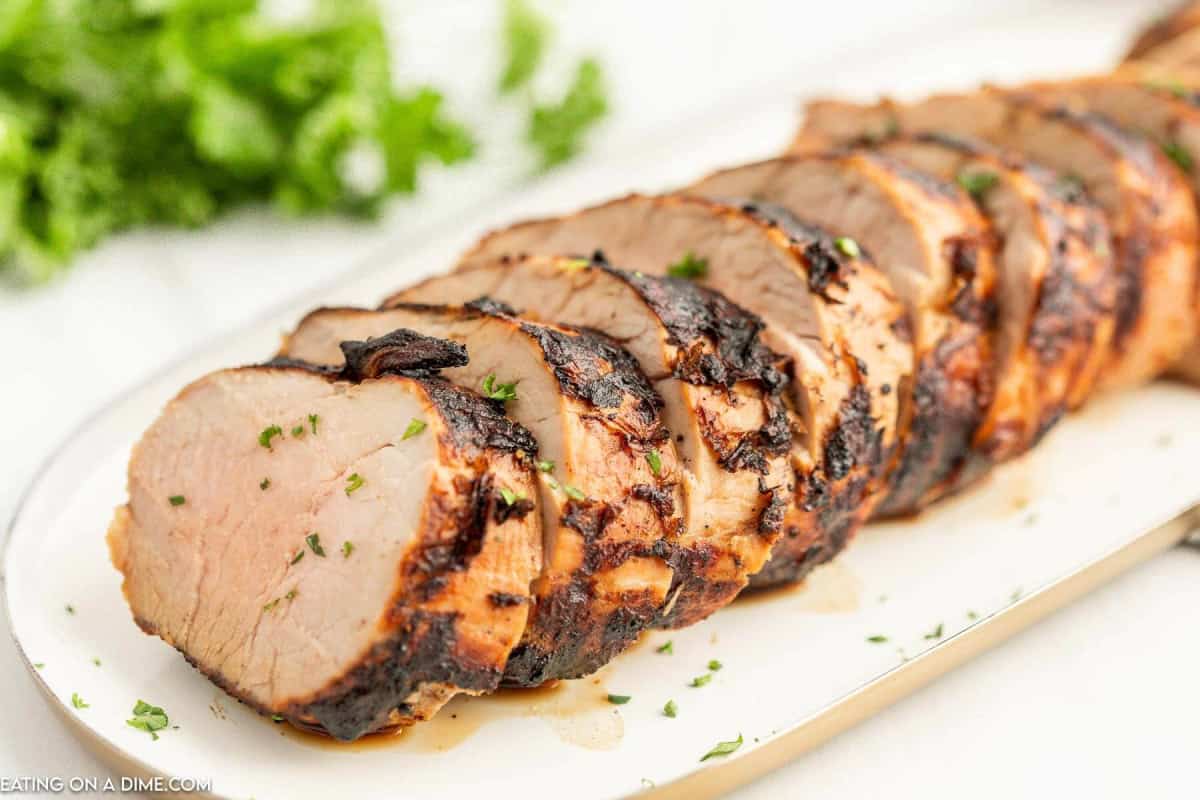 Grilled Pork Tenderloin sliced and served on a white platter.