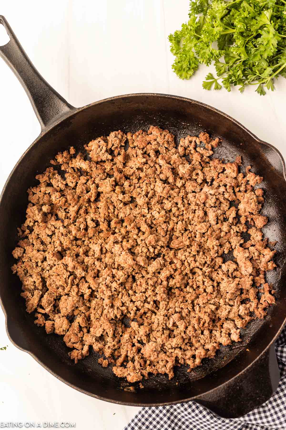 cooking the ground beef in a cast iron skillet