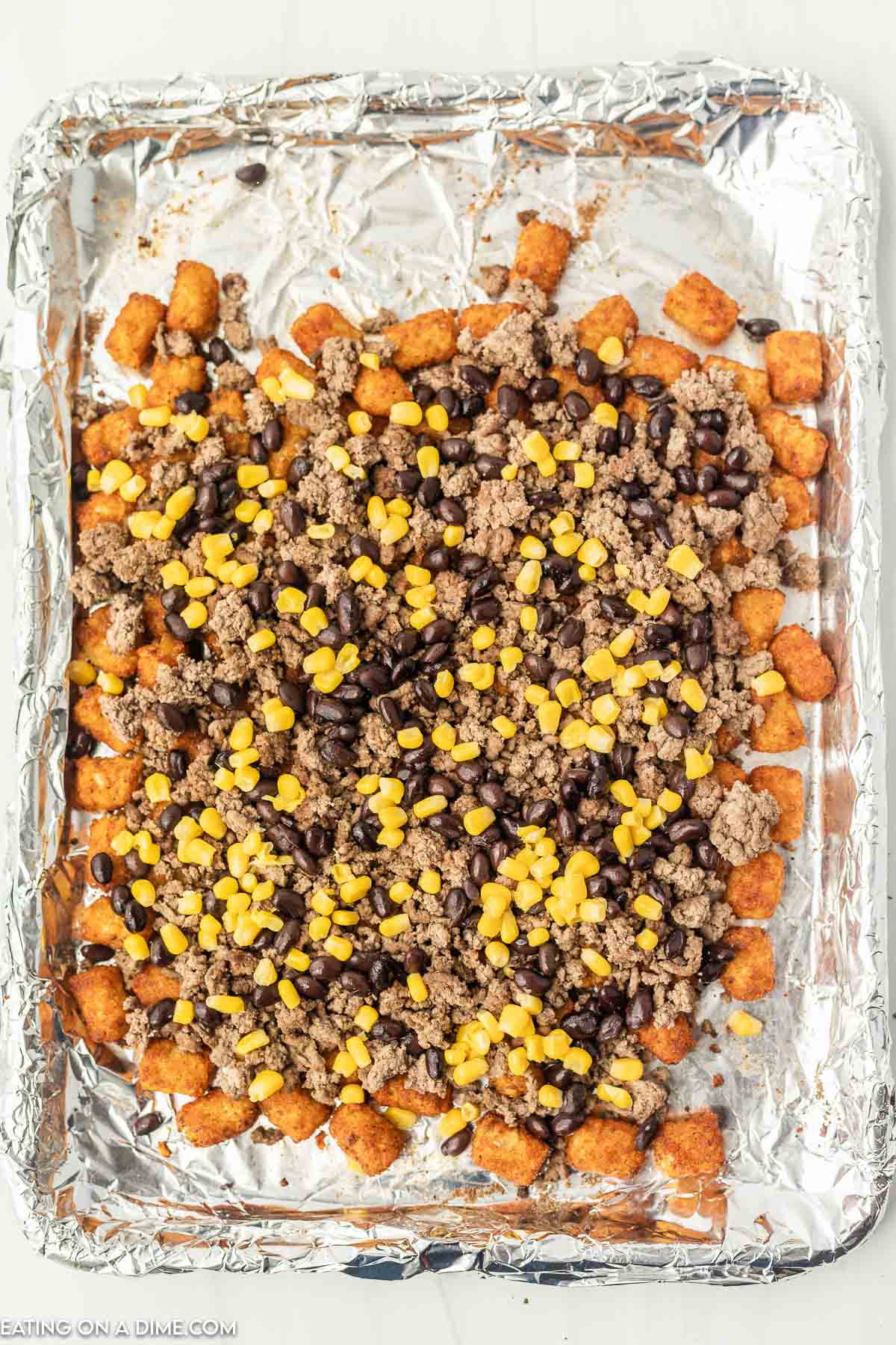 Top with tator tots with ground beef, black beans and corn