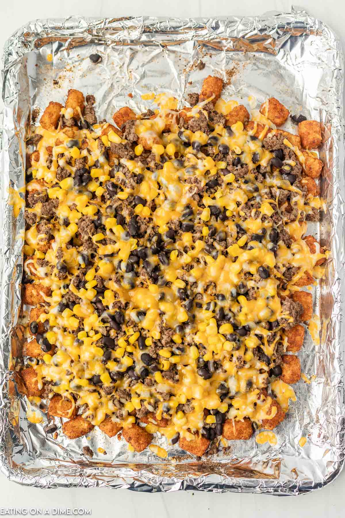 Top the tator tots with cheese, beans, corn
