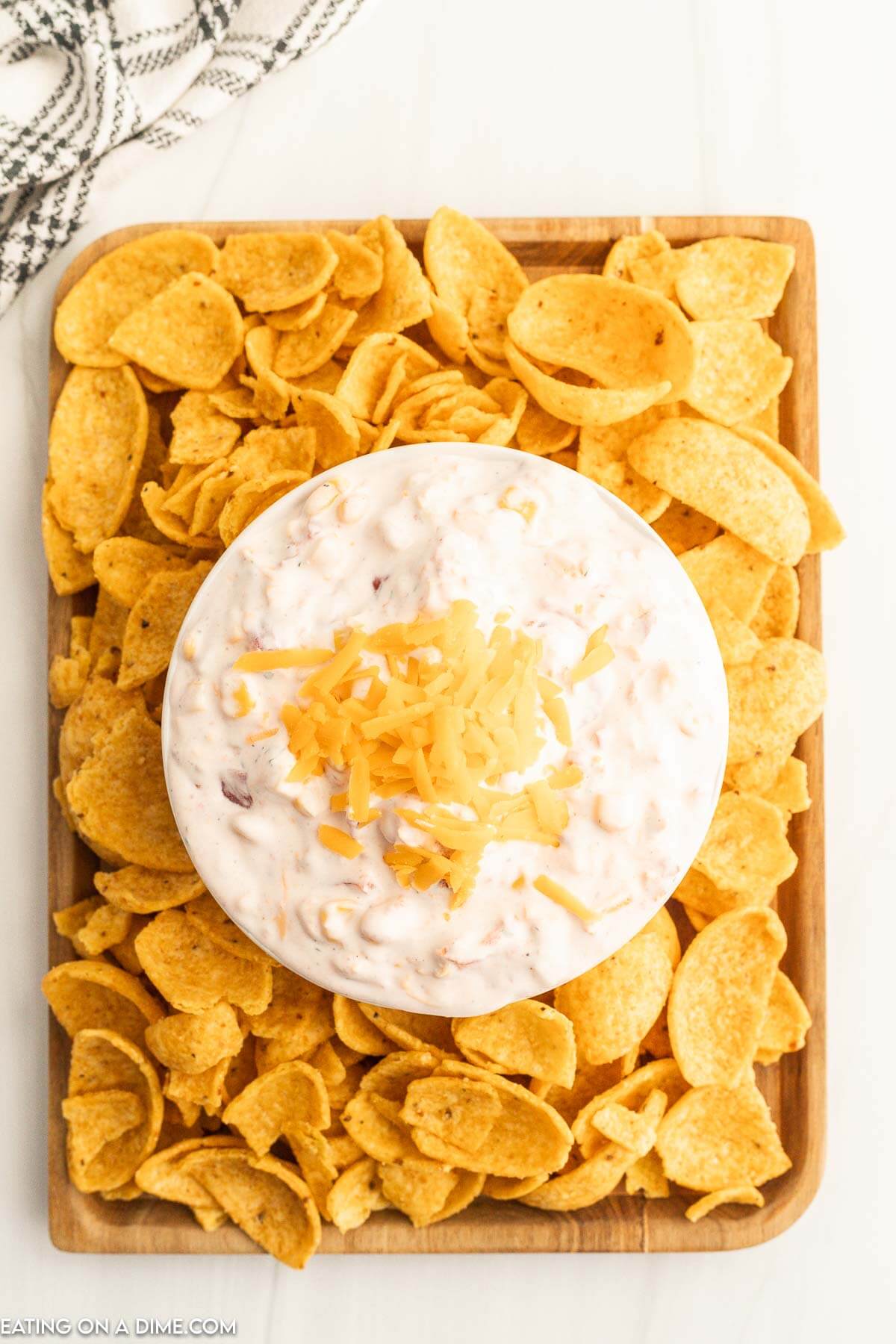 Fiesta Ranch Dip topped with cheese in a bowl with a side of corn chips