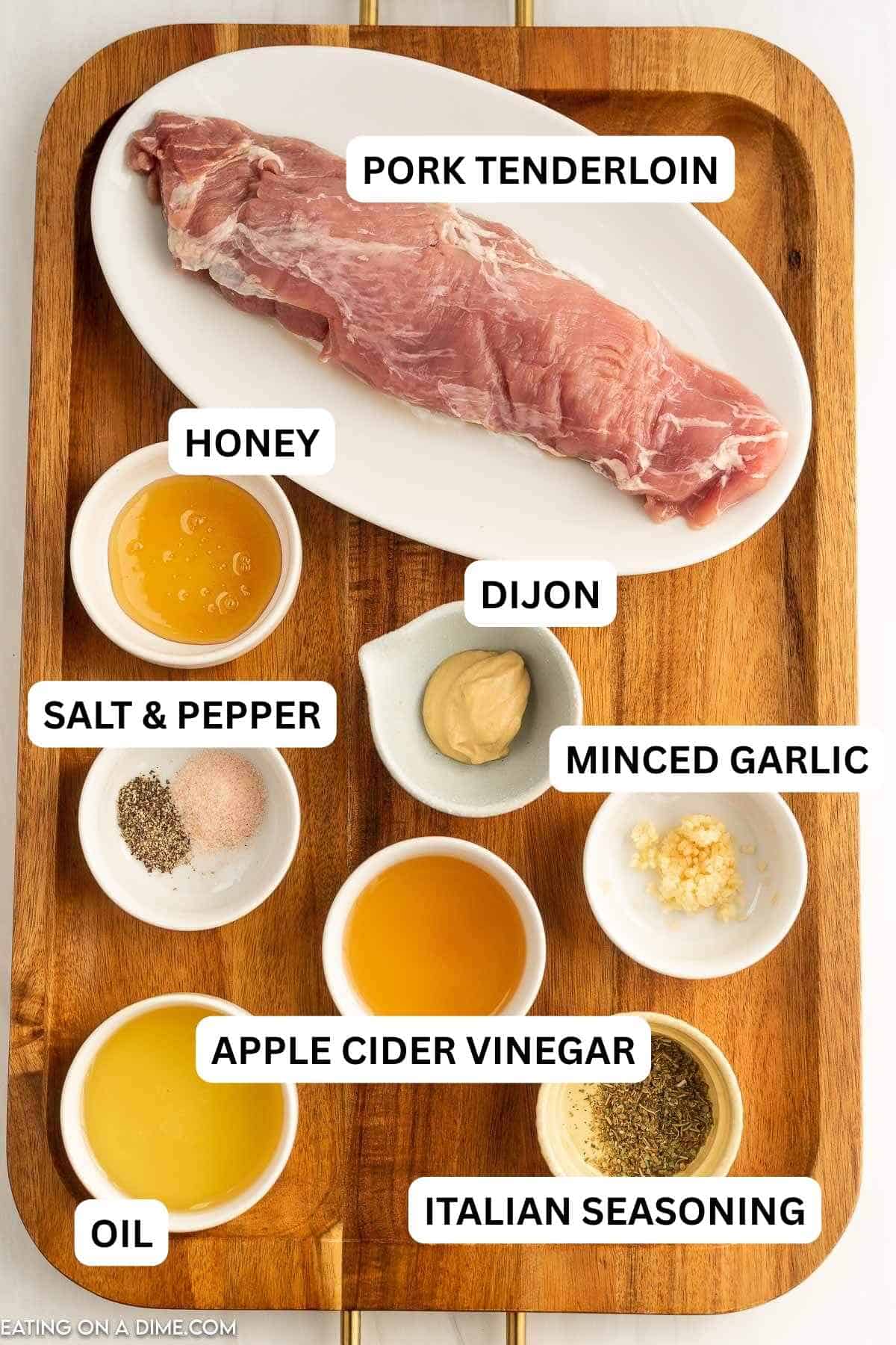 The ingredients required to make the recipe prepared on a wooden board. Includes pork tenderloin, dijon, honey and more.