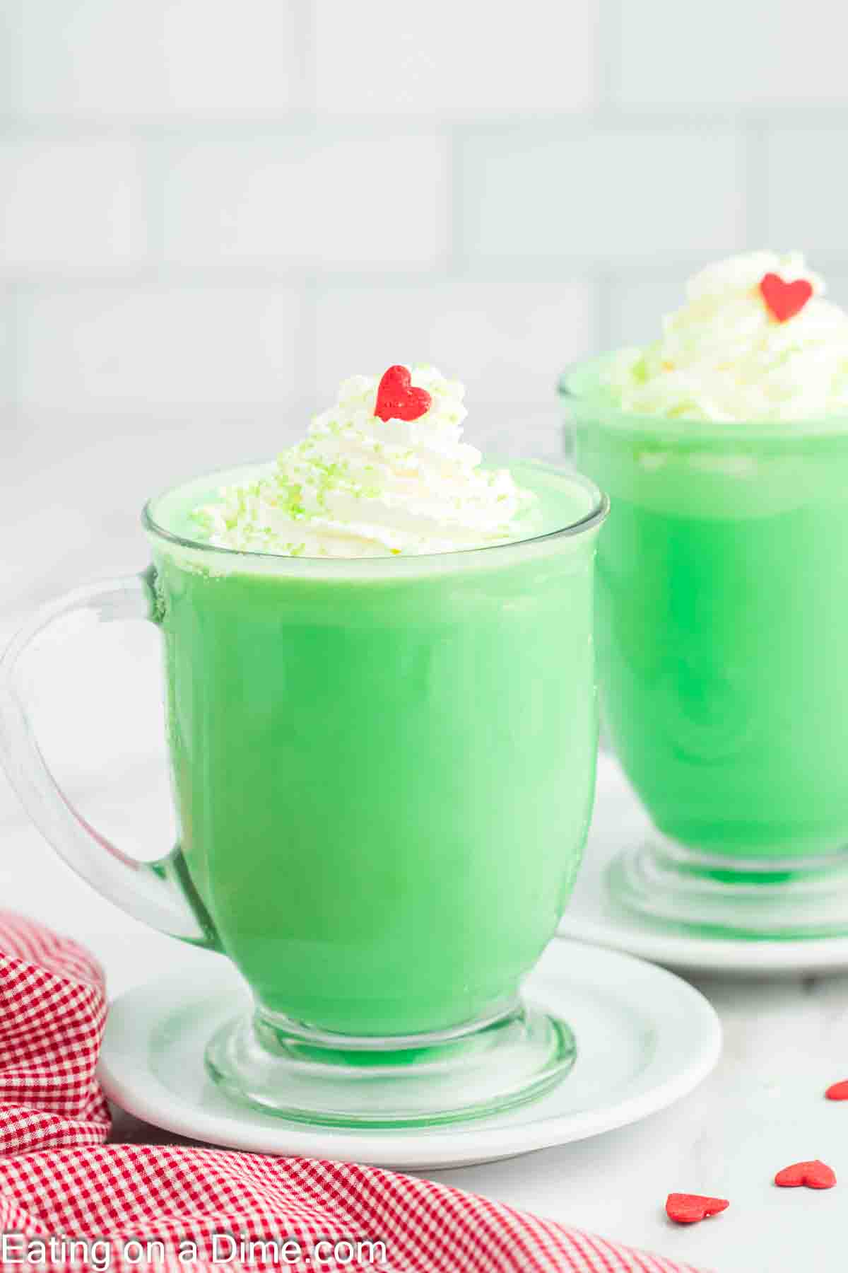 Grinch Hot Chocolate in mugs and topped with whipped cream and red heart