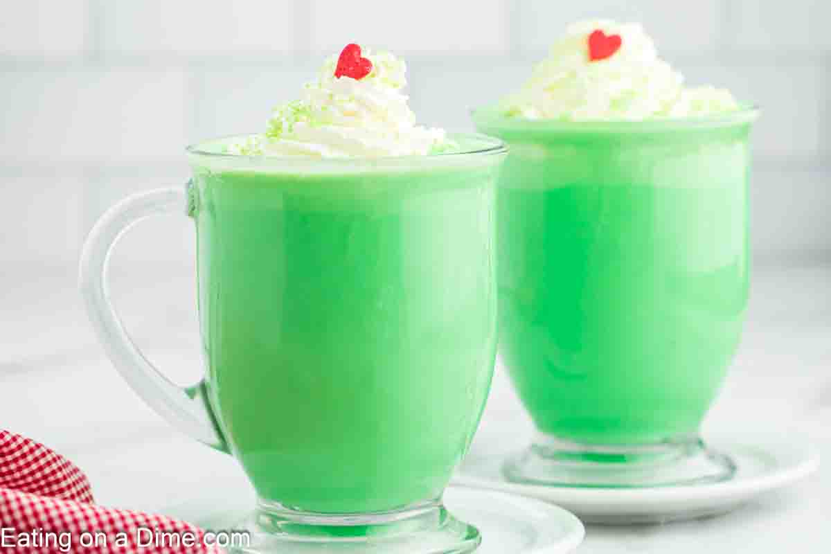 Grinch Hot Chocolate in mugs and topped with whipped cream and red heart