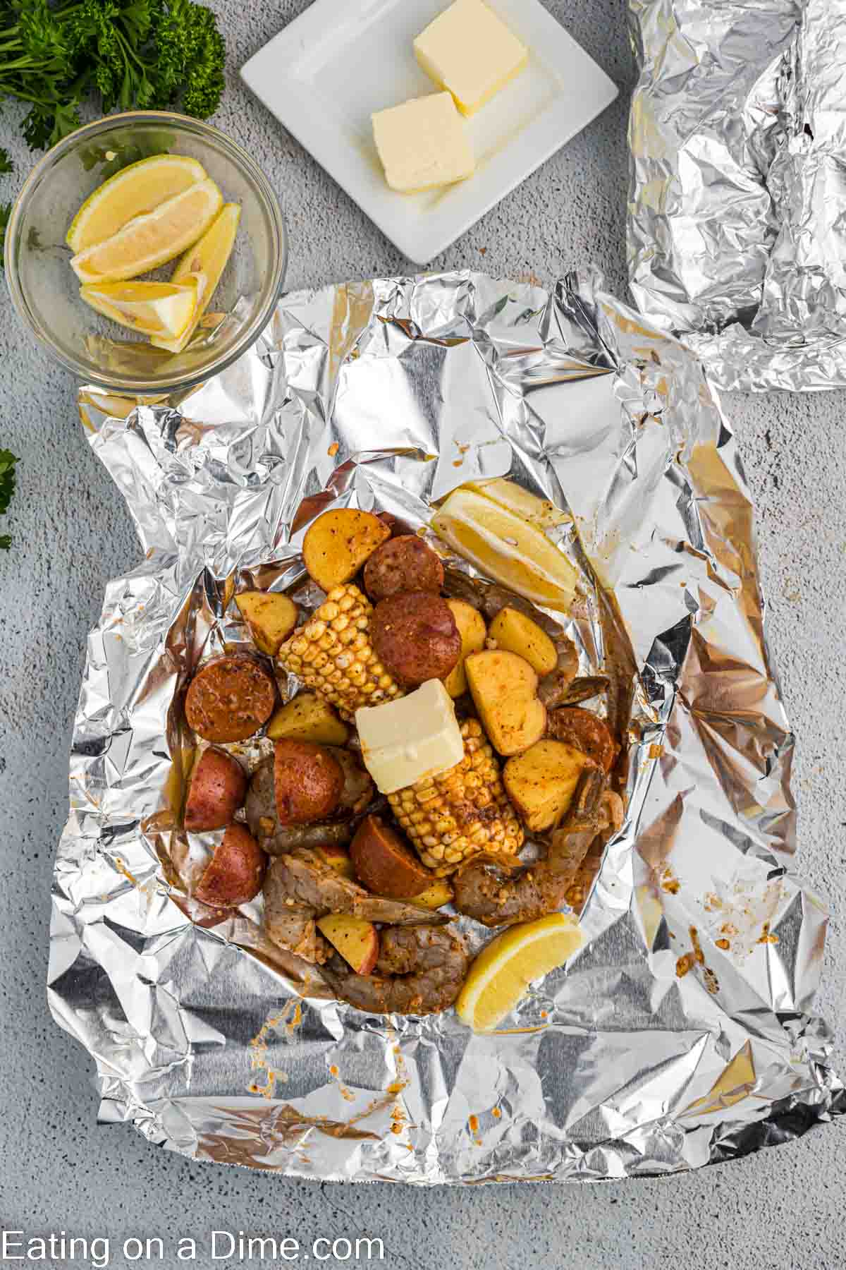 Seasoned shrimp, sausage, potatoes, corn, lemon and butter on a piece of foil