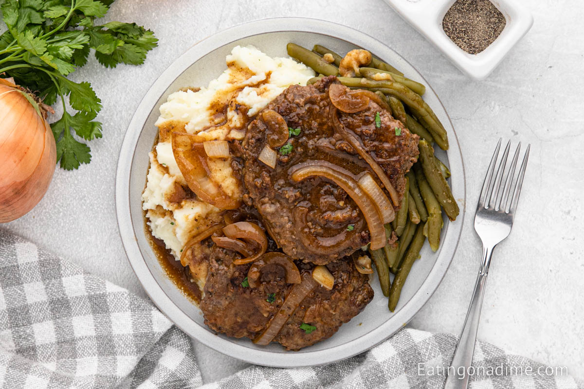 Cube Steak and gravy on a plate with mashed potatoes and green beans
