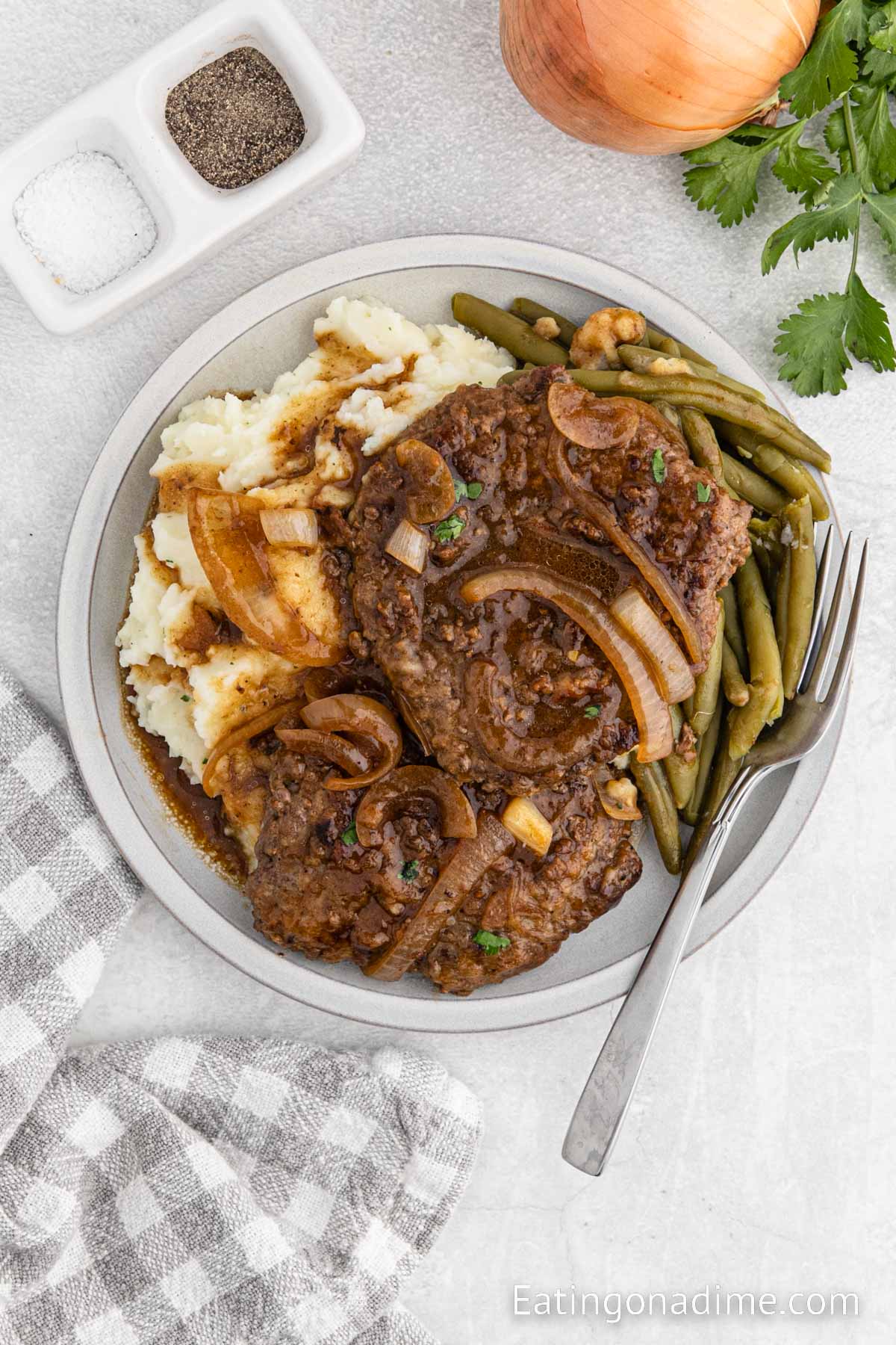 Cube Steak and gravy on a plate with mashed potatoes and green beans