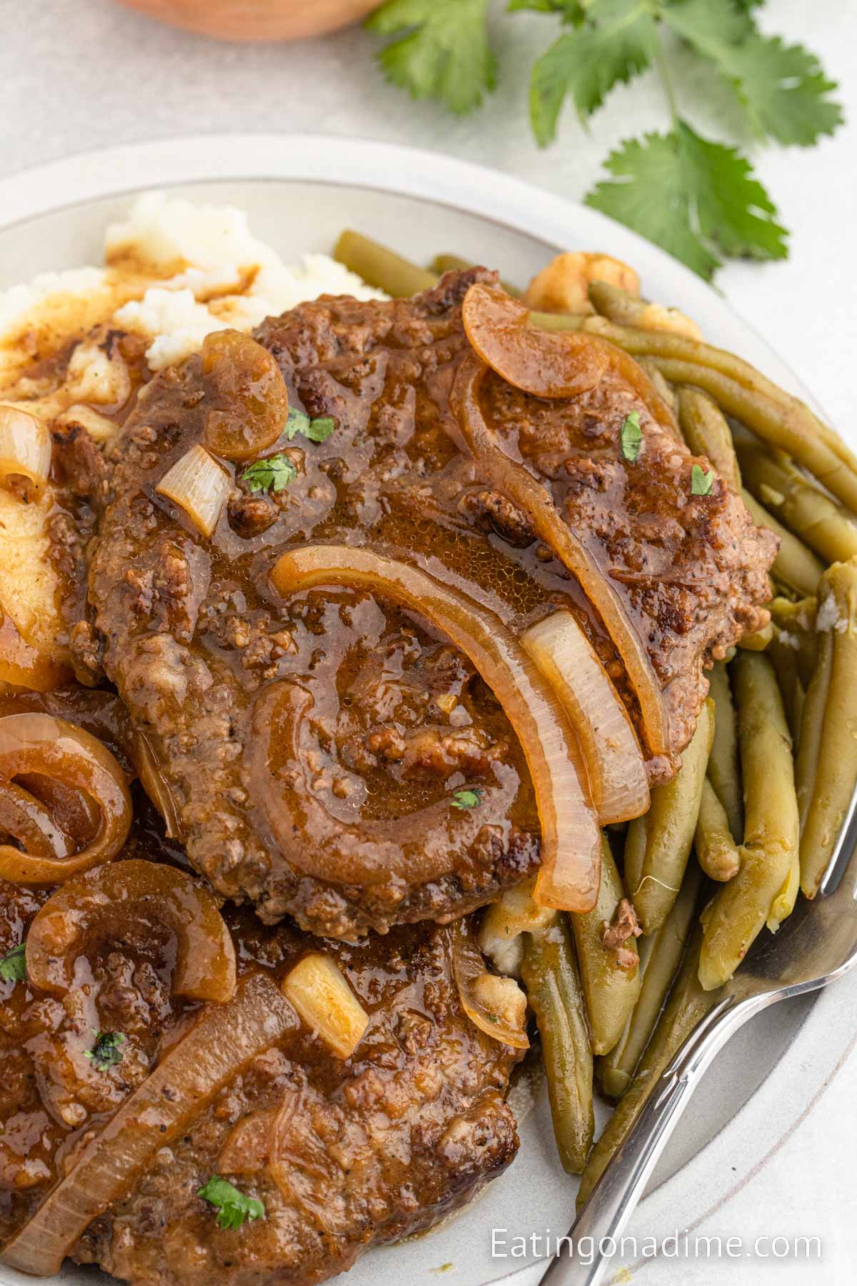 Cube Steak and gravy on a plate with mashed potatoes and green beans