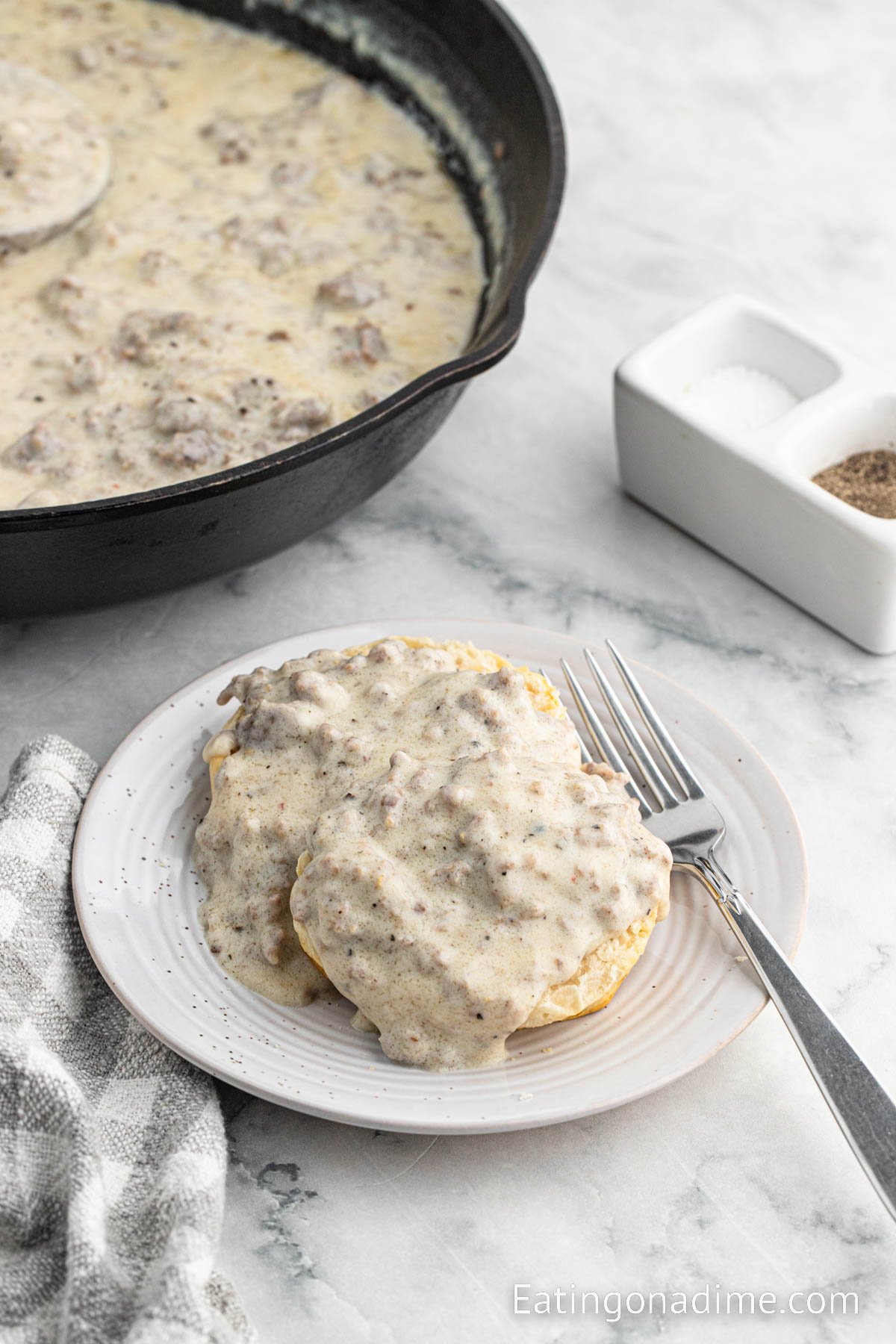 Sausage gravy over biscuits on a plate with a fork