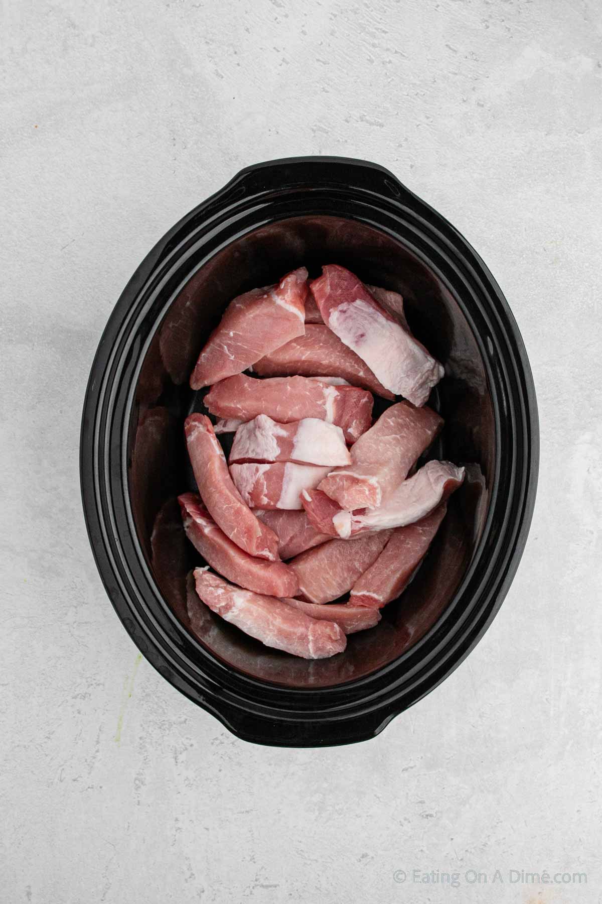 Uncooked pork ribs stacked in the slow cooker