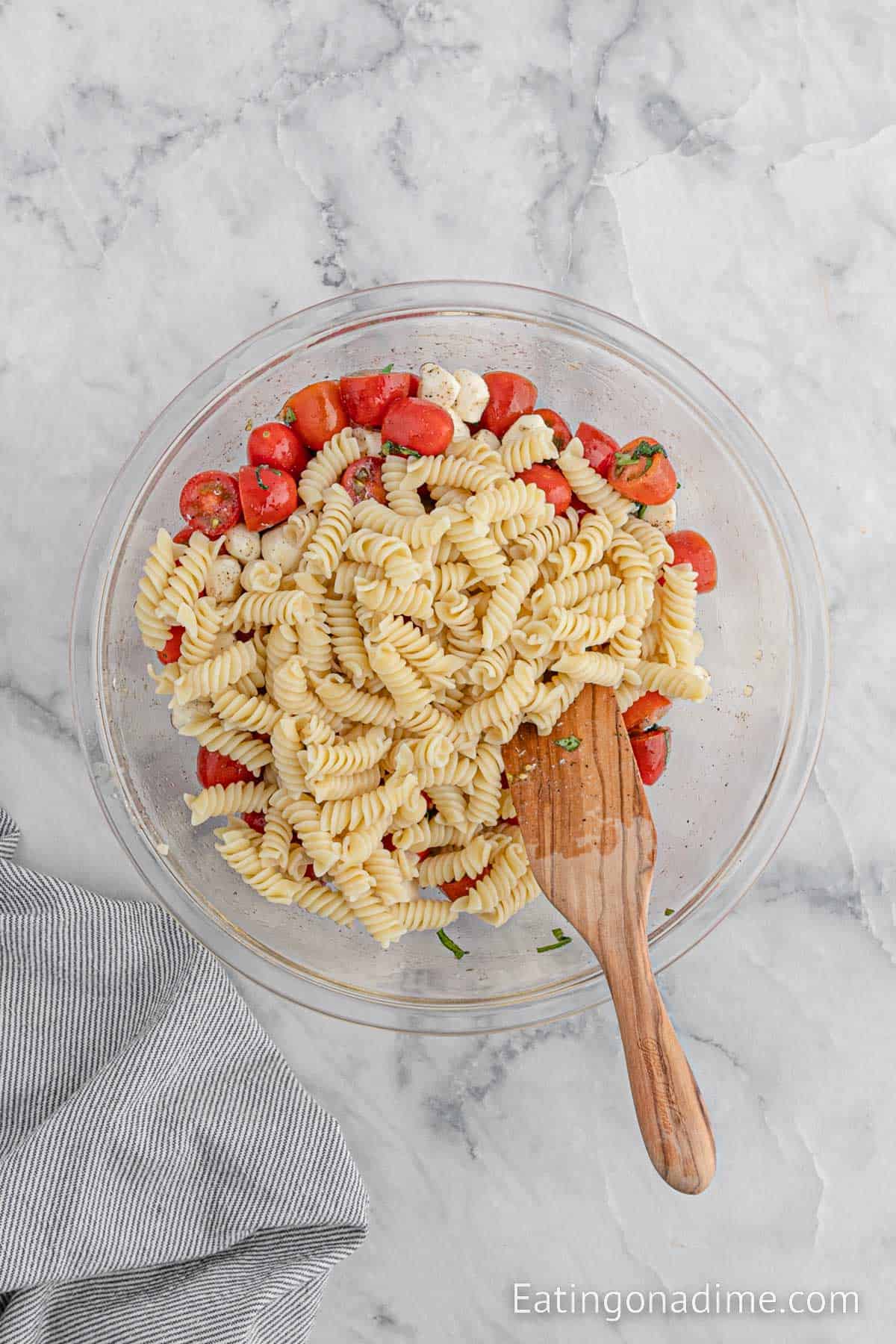 Mixing in the pasta with the other ingredients in a bowl with a wooden spoon