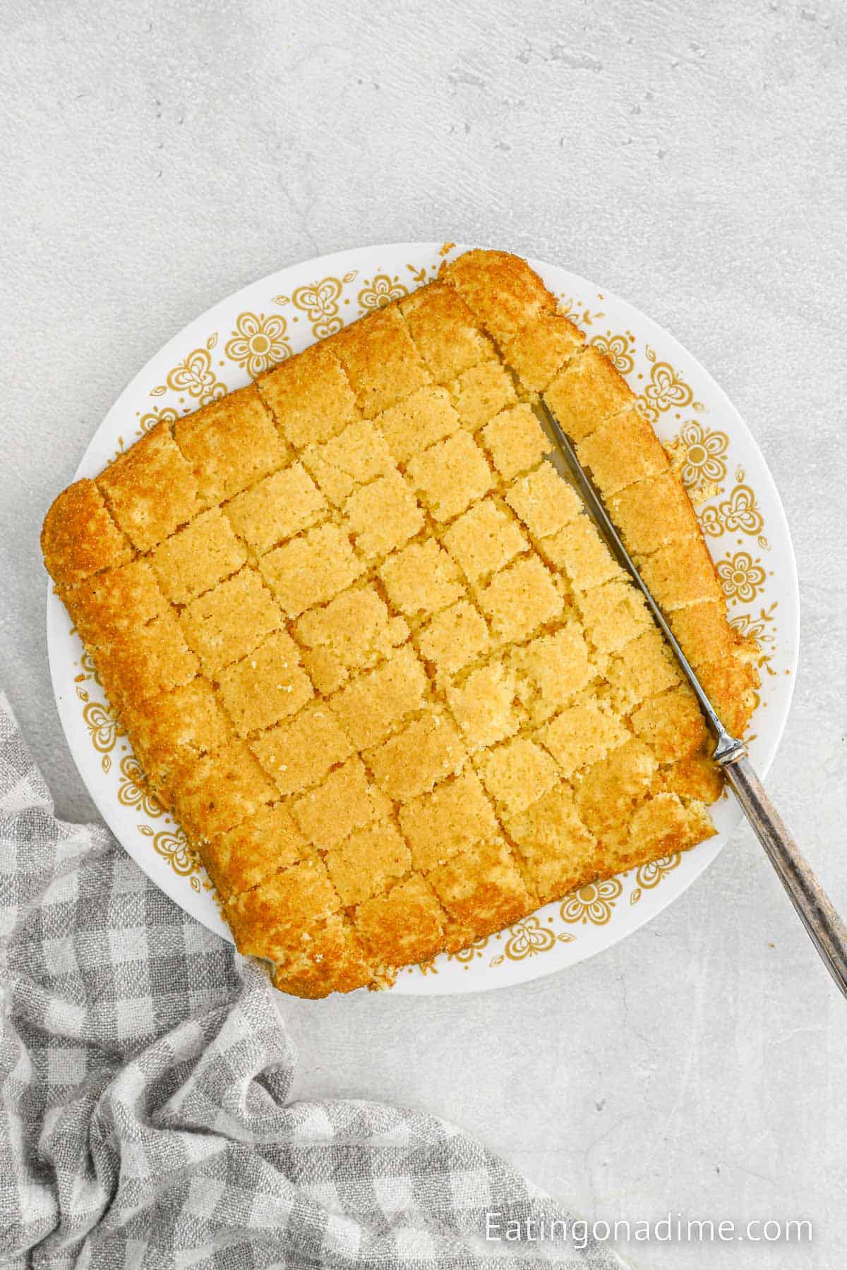 Cutting the baked cornbread into cubes on a plate